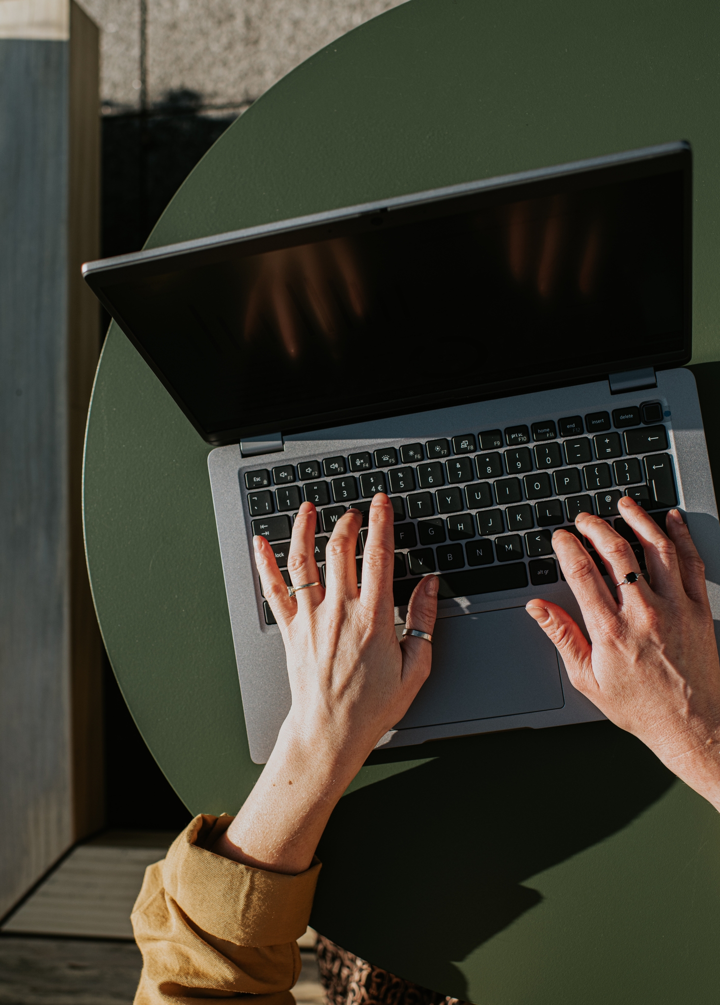 Close-up of a idiosyncratic typing connected a laptop with some hands, seated astatine a circular array with portion of a sleeve visible