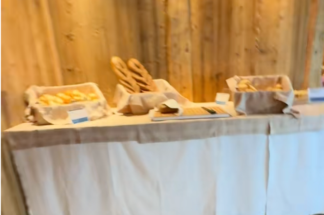 テーブルに置かれたバスケットには、様々な種類のパンが並んでいる。背景は木材の壁。