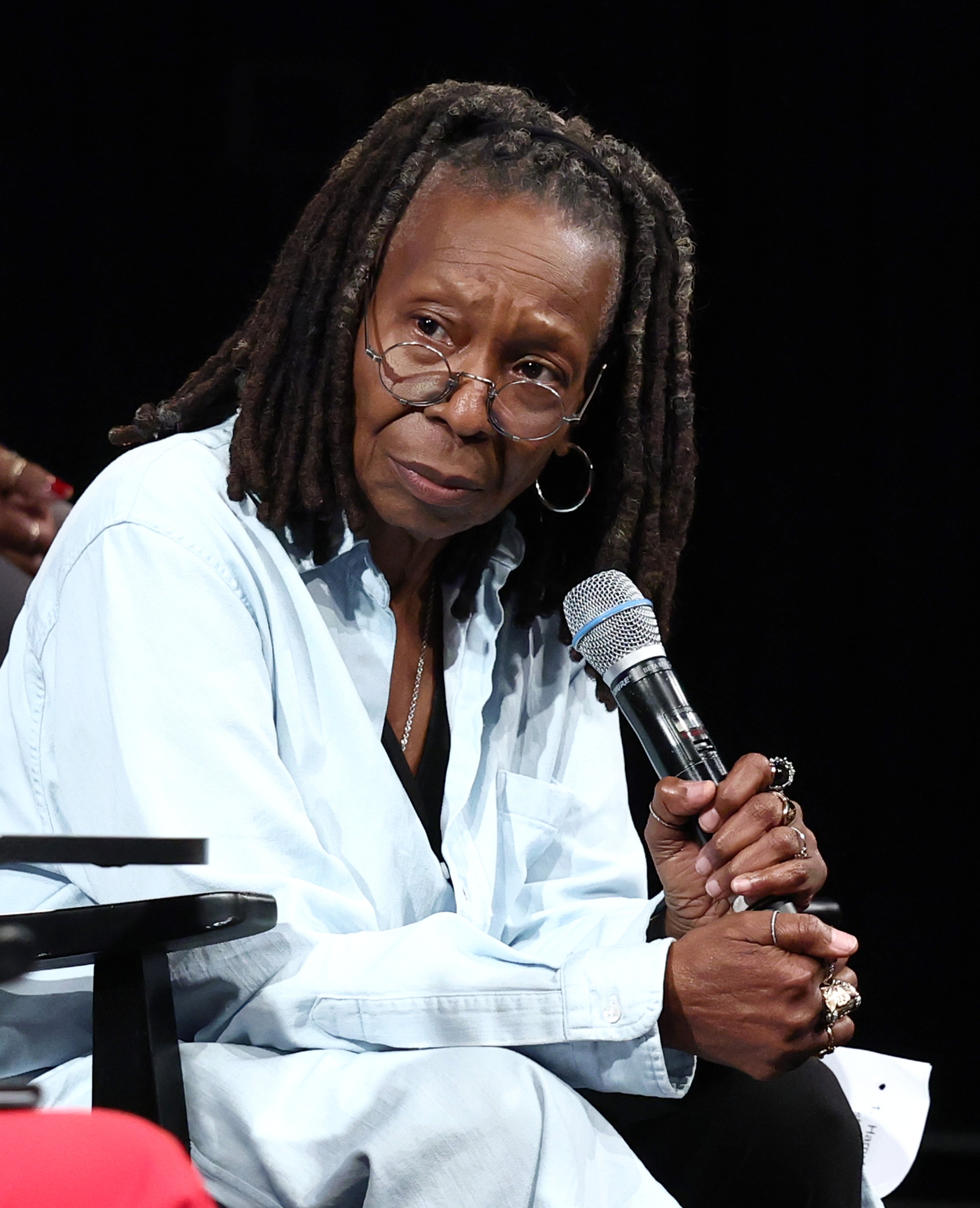 Whoopi holding a microphone during a sheet  discussion