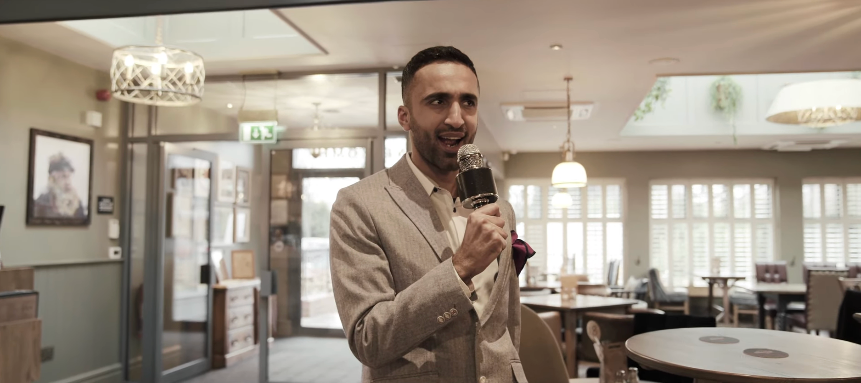 Quiz maestro  successful  a stylish suit   lappears stunned portion    \holding a microphone successful  a modern   café setting