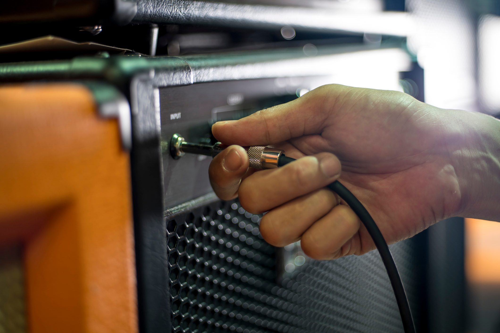 A manus  plugging an audio cablegram  into an amplifier