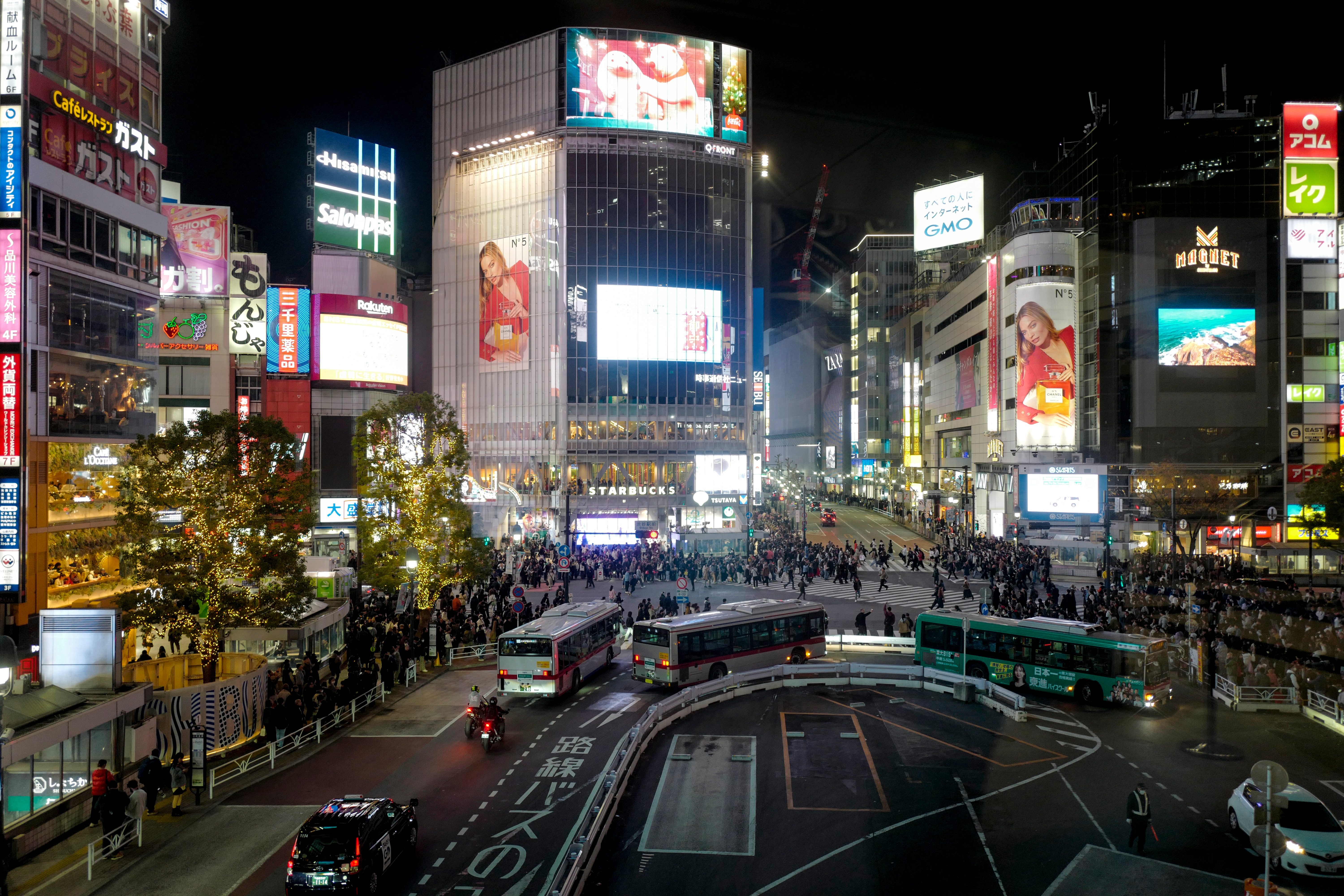 Busy Shibuya Crossing astatine  night, crowded with radical   and surrounded by illuminated billboards, including recognizable marque  advertisements