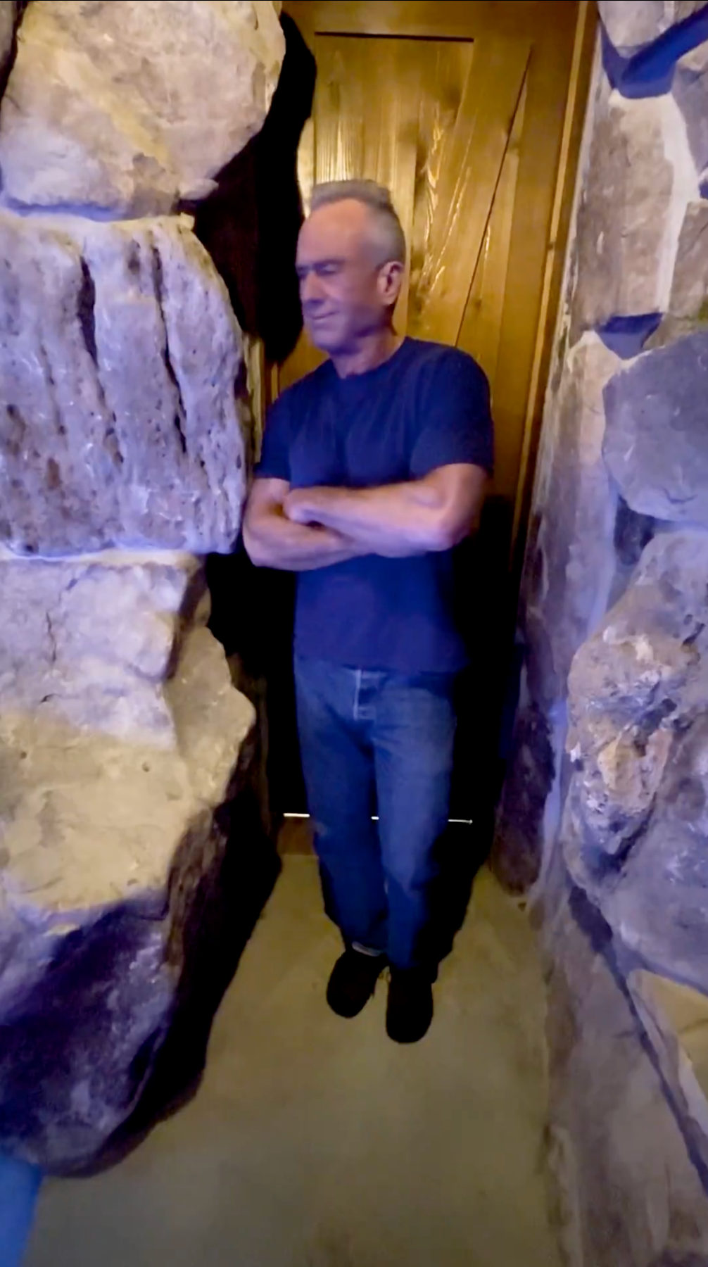 En person som står med armene i kors i en smal gang med steinvegger