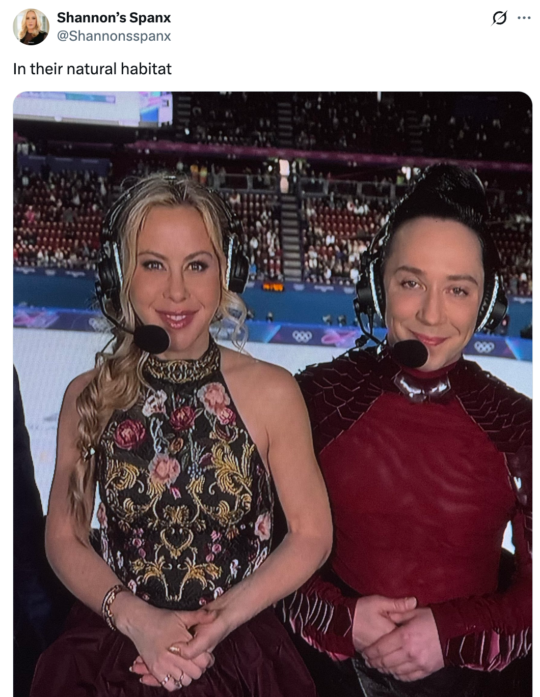 To personer med headset står innendørs. Den ene er i et floral grimeantrekk, den andre i et teksturert rødt ensemble. Begge smiler