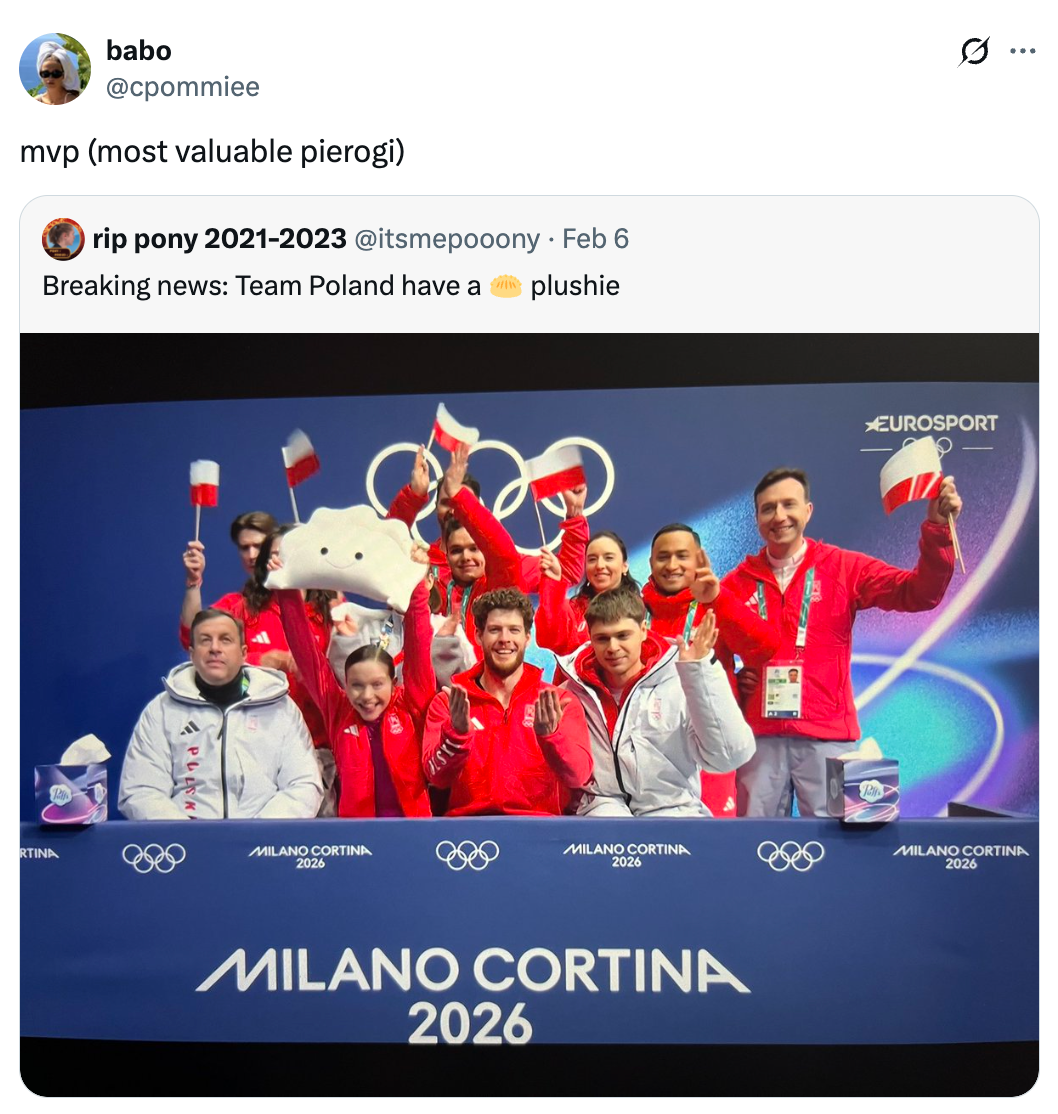 En gruppe idrettsutøvere i røde treningsdrakter som feirer, holder flagg og en skyplysj, sittende foran et banner med teksten