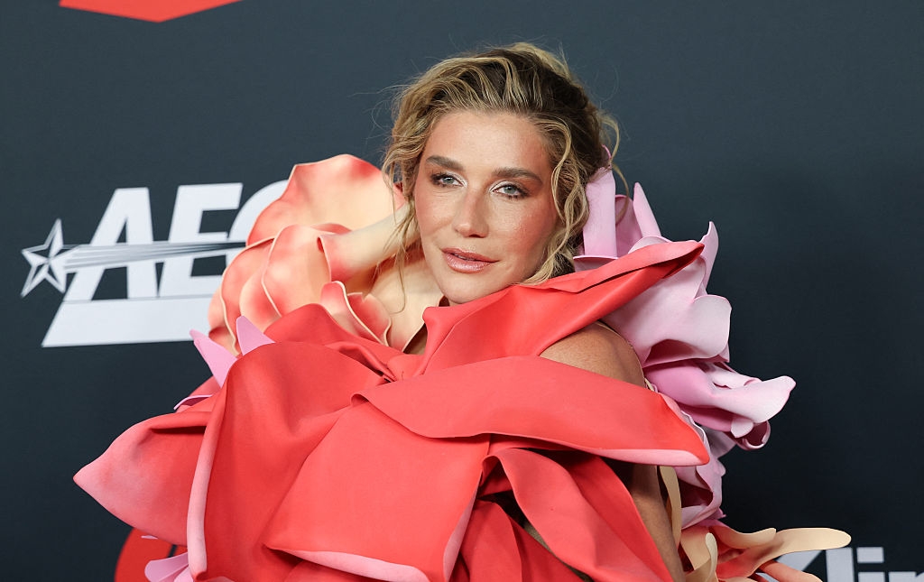 Person successful  a dramatic, floral-structured gown with layered cloth  poses connected  the carpet successful  beforehand   of a backdrop with logos