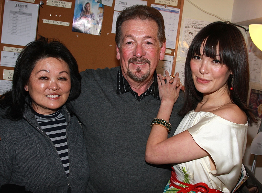 Three radical   airs  intimately  together, smiling. The idiosyncratic   connected  the close    wears a shiny off-shoulder outfit, adding an elegant touch