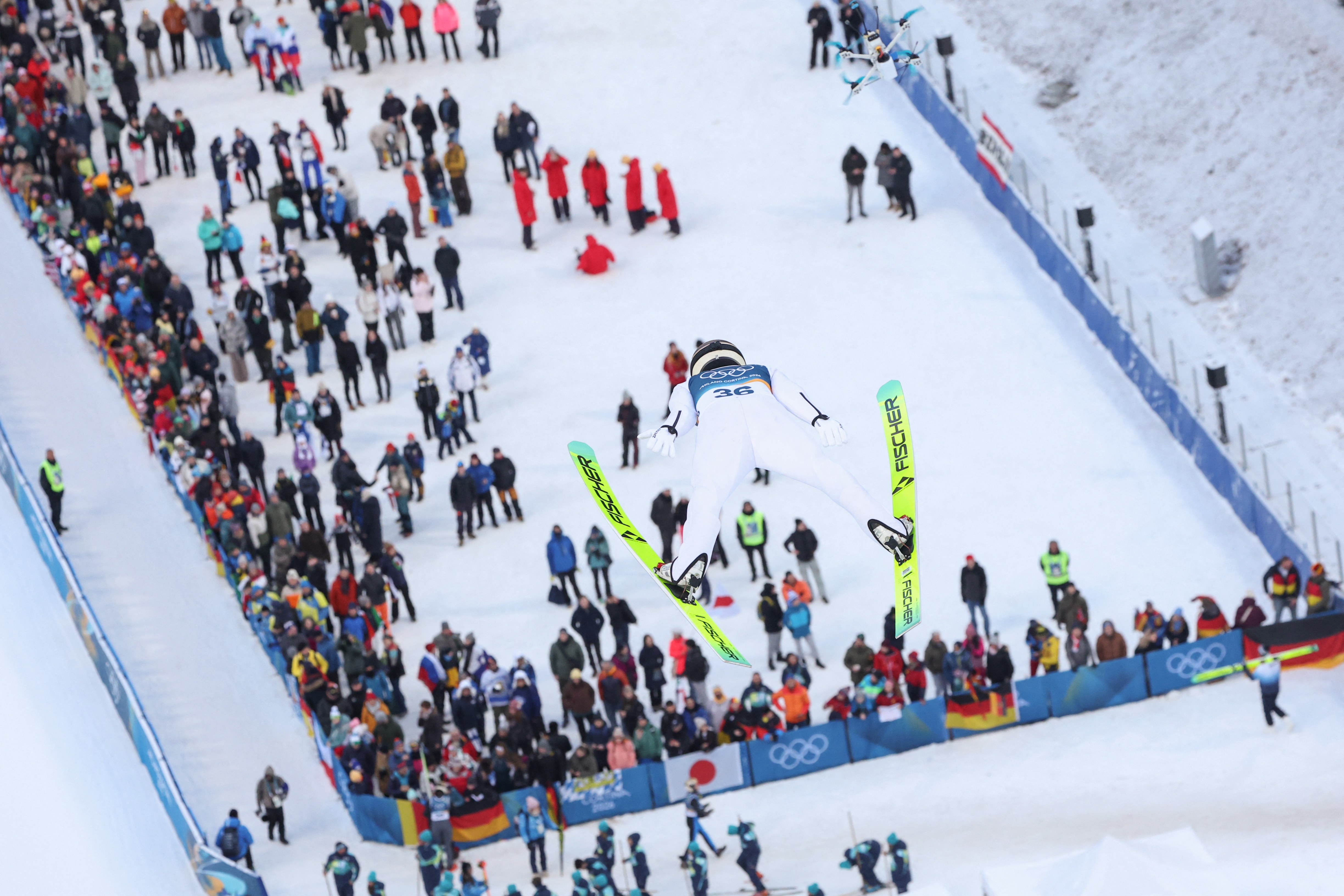 Skiløper midt i luften ved OL-arrangement, utfører hopp over publikum, viser intrikate triks og atletikk