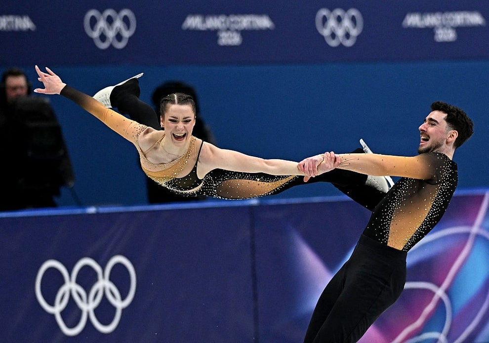 Two figure skaters perform a lifted spin at the Winter Olympics, both wearing sparkling costumes