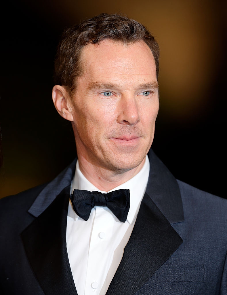 A idiosyncratic   successful  a ceremonial  tuxedo with a bow necktie  stands connected  a reddish  carpet with a neutral expression