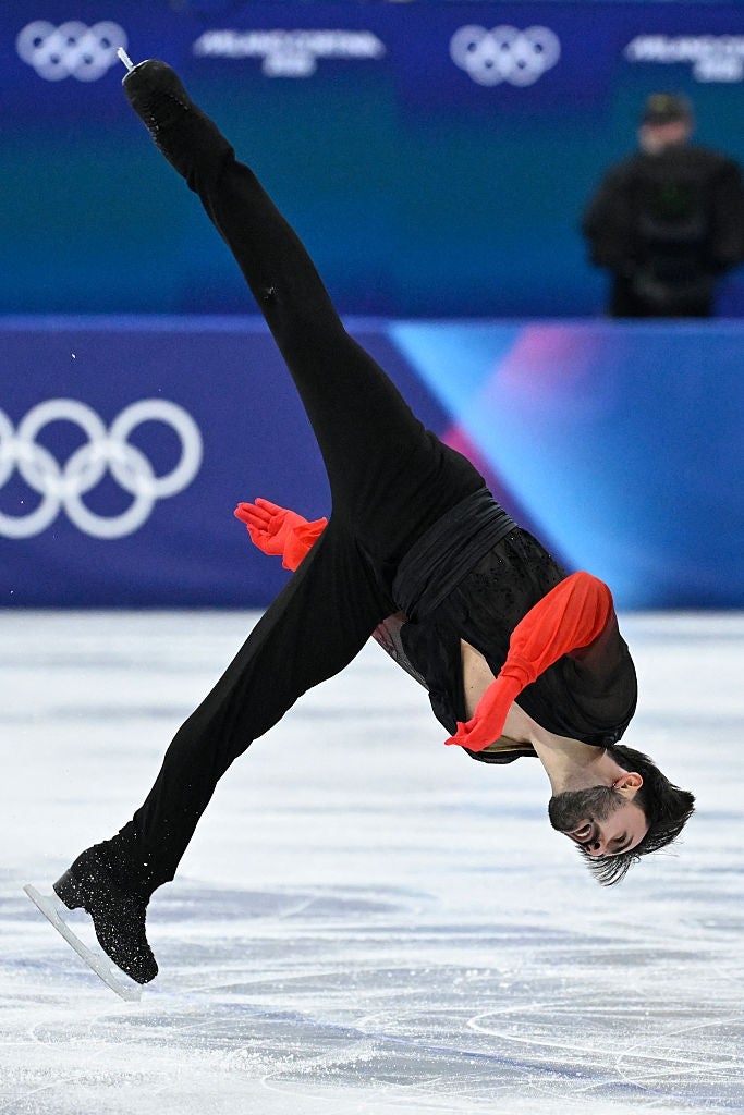 Figure skater in mid-air with one leg extended, performing a spin on the ice rink at a competitive event
