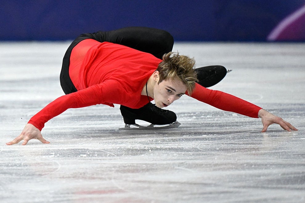 Figure skater in a dynamic pose on the ice, wearing a fitted long-sleeve top