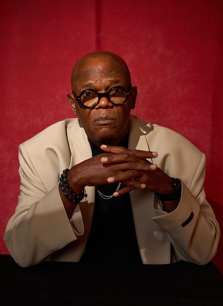 Person successful  a airy  blazer with circular  glasses poses thoughtfully with hands clasped against a coagulated  background