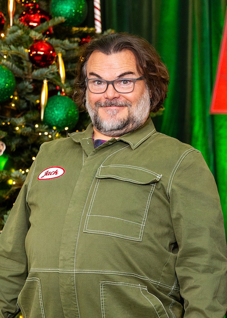 Person successful  greenish  jumpsuit with patches, posing successful  beforehand   of a holiday-themed inheritance  with decorated tree