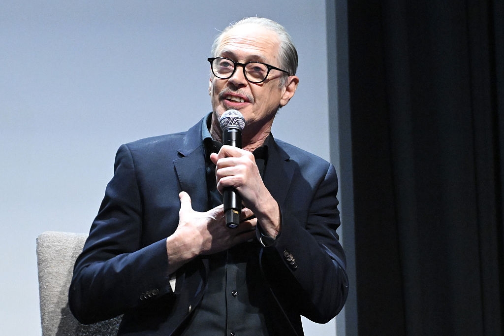 Man successful  a suit   speaks into a microphone, gesturing with his hand, connected  a stage