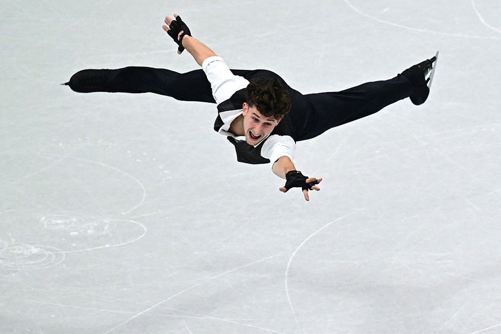 Figure skater performs an impressive mid-air split jump on the ice, showcasing skill and athleticism during a routine
