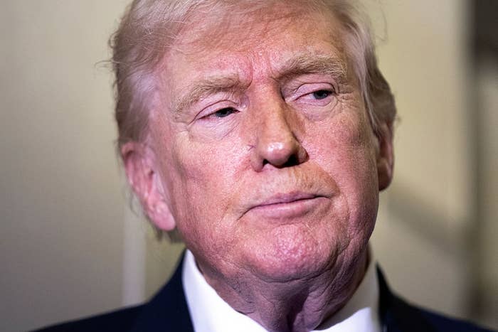 A man in a suit is looking to the side with a neutral expression