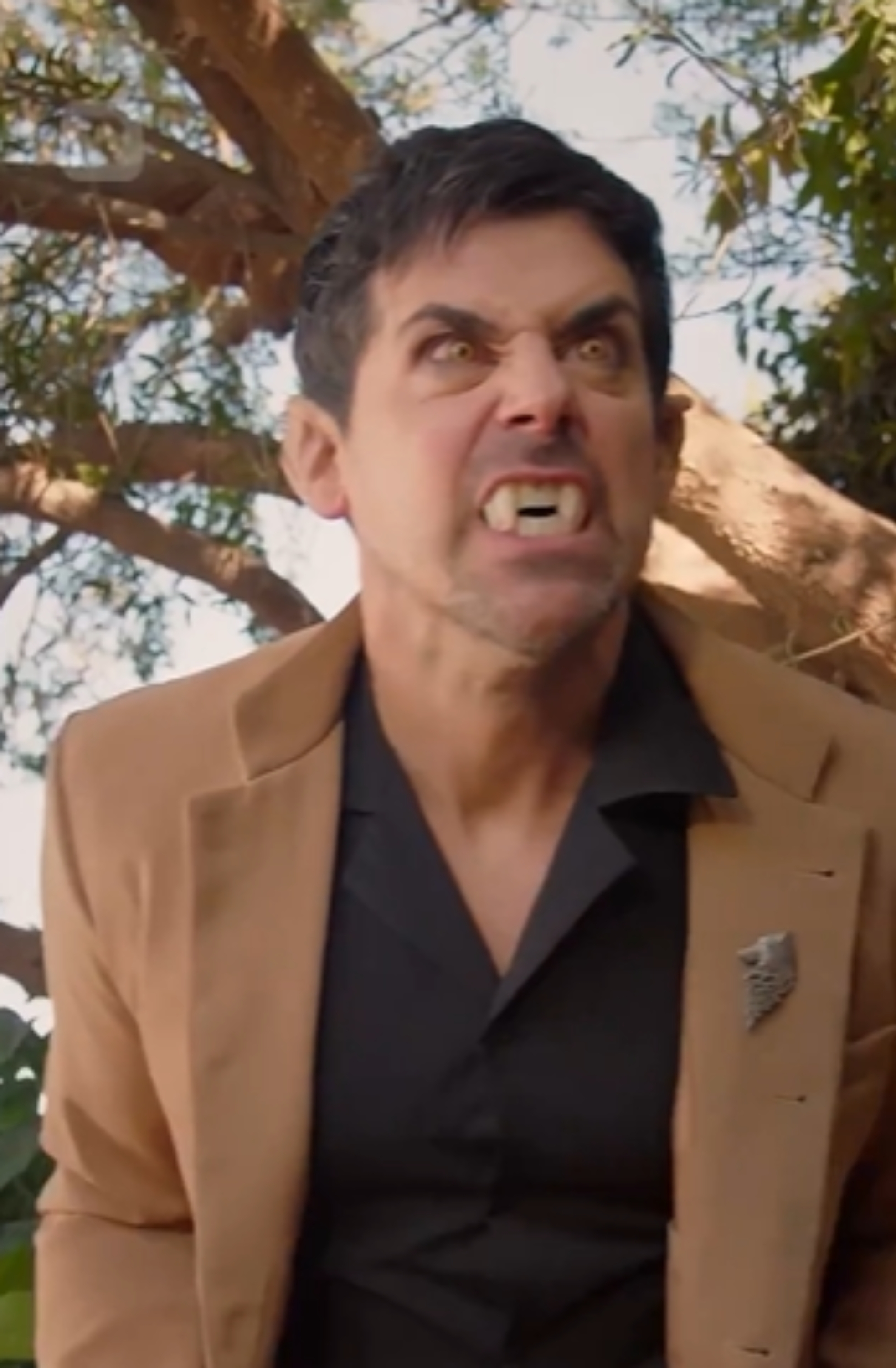 Silhuett av en ulv som hyler på en høyde med en stor, fullmåne og trær i bakgrunnen