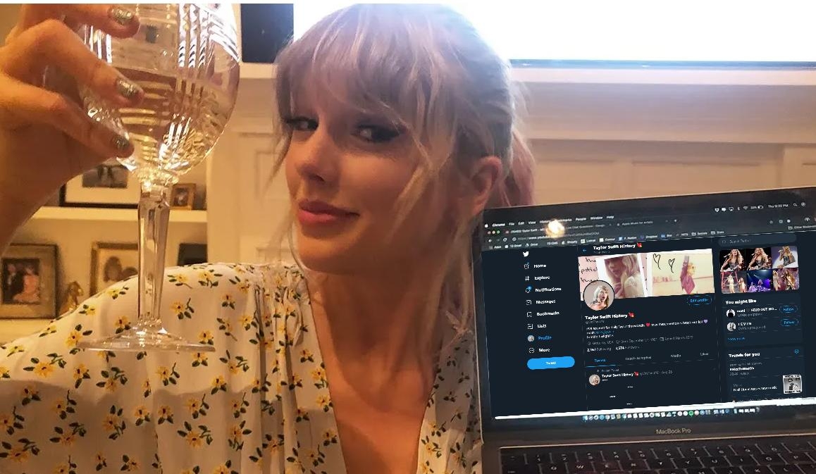 Person in floral outfit raises a wine glass, smiling at the camera. Holds a laptop displaying a Twitter profile, possibly celebrating an announcement