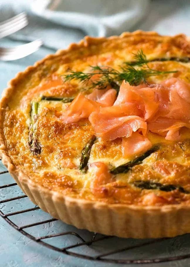Quiche with smoked salmon and asparagus connected  a ligament  rack, garnished with caller  dill