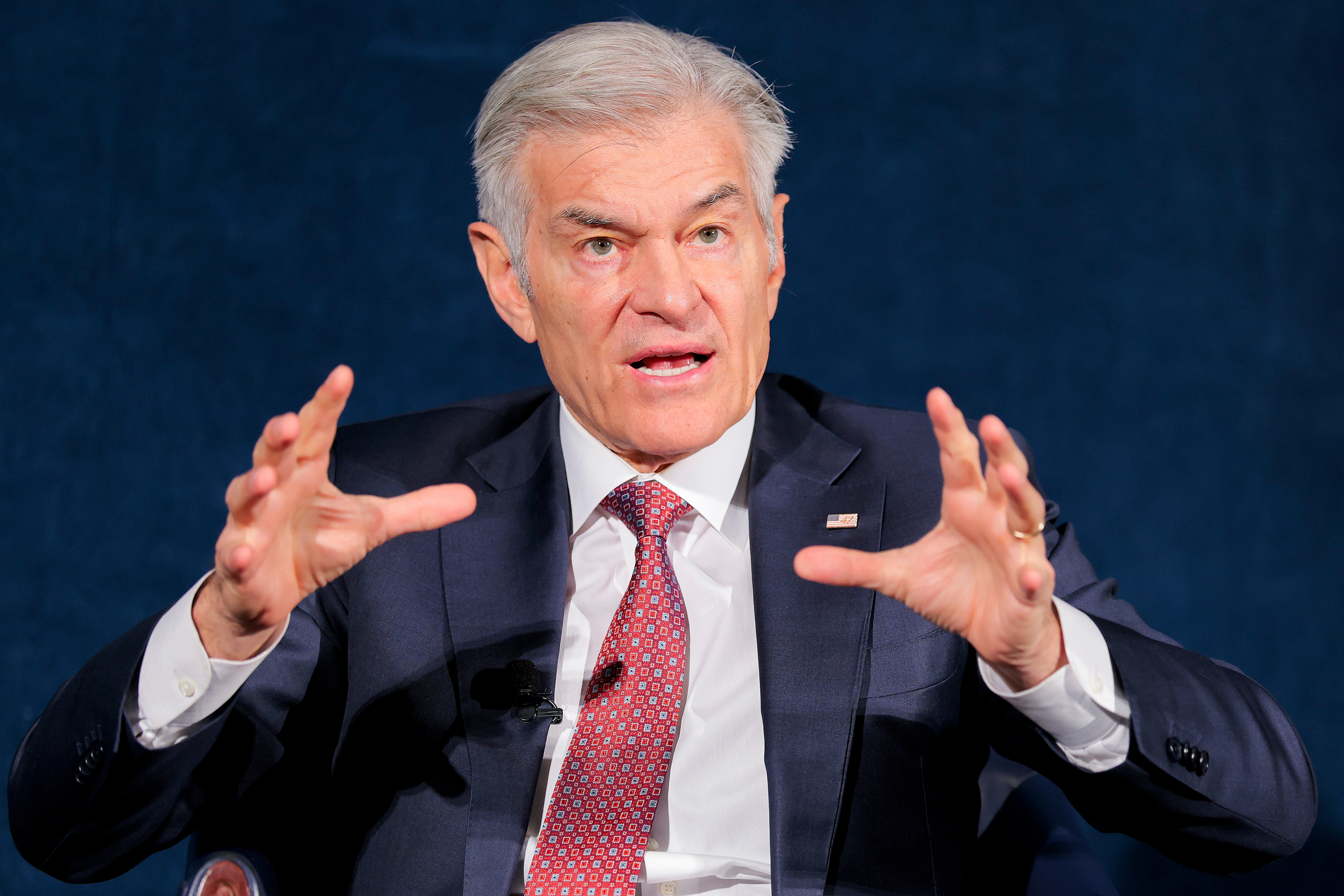 En person som snakker lidenskapelig, iført dress og slips, gestikulerer med begge hender