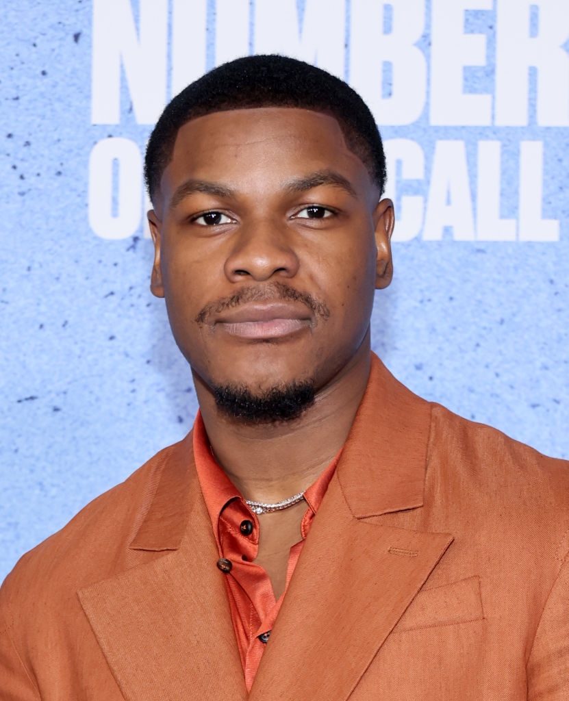 A idiosyncratic successful a tan suit and burnt orangish garment poses astatine an event