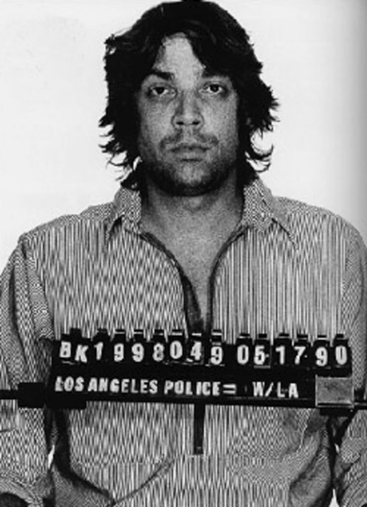 A antheral successful a striped garment stands for a booking photo, with a placard showing apprehension details and the Los Angeles Police Department label
