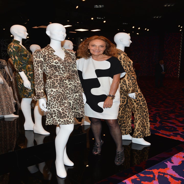 Uma mulher com manequins vestidos com roupas com estampa de leopardo em um evento de moda, usando um vestido estampado preto e branco