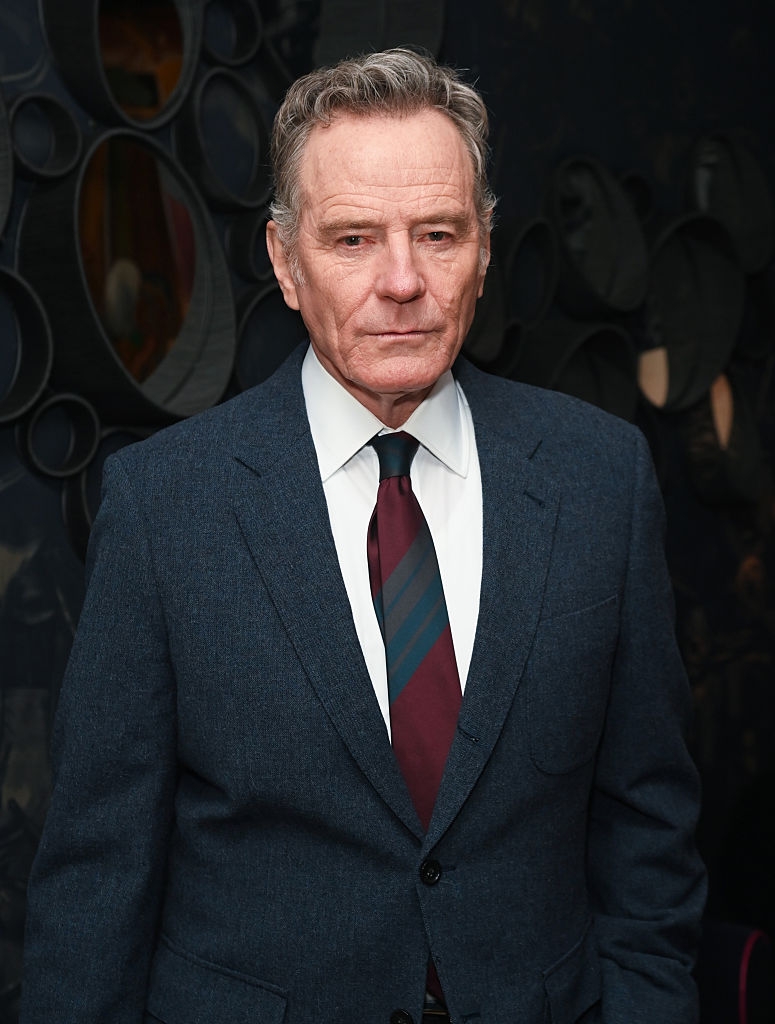 Man wearing a tailored suit with a patterned tie, lasting against a textured backdrop