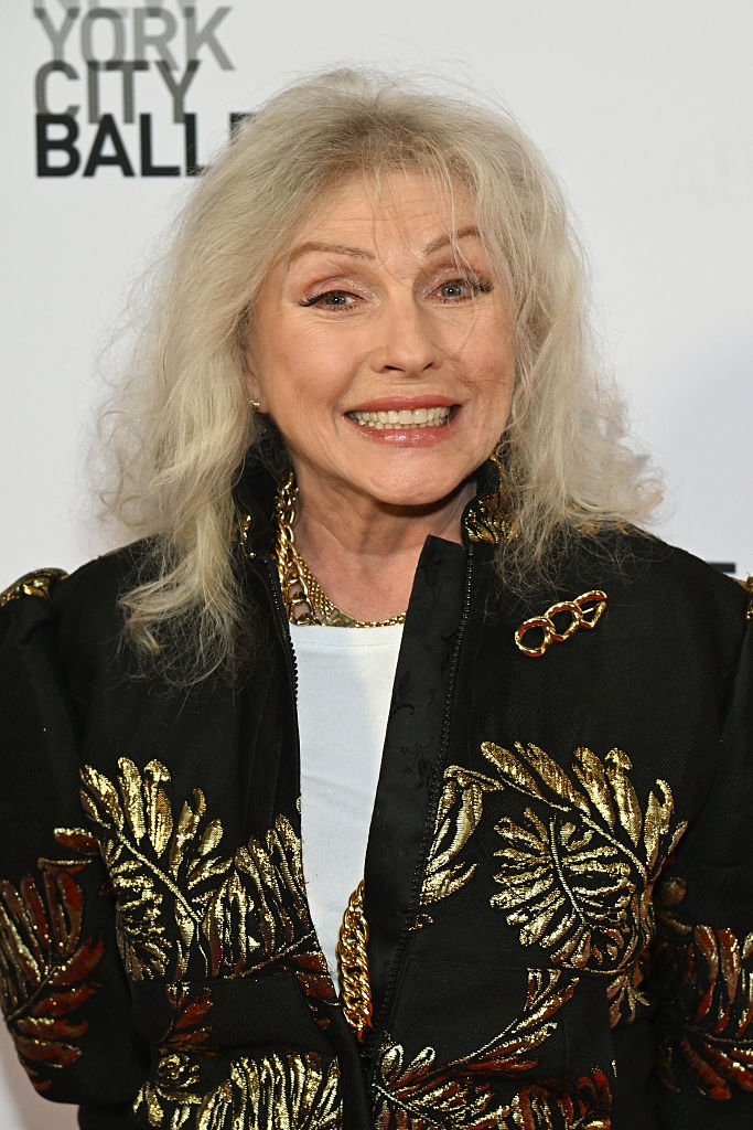 Celebrity successful embroidered overgarment smiles astatine an lawsuit with a New York City Ballet backdrop