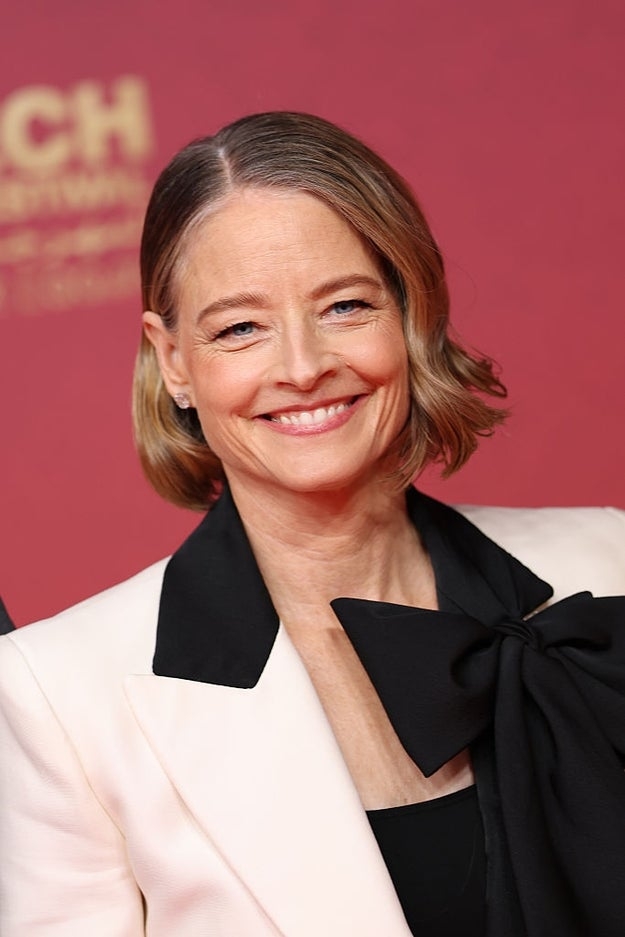 Person connected reddish carpet wearing a tailored suit with a ample bow