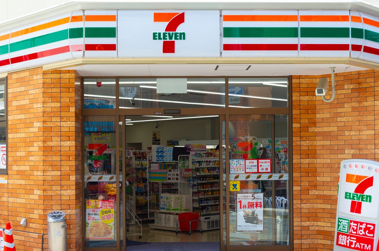セブンイレブンの店舗外観。自動ドアを通して店内の商品棚が見える。