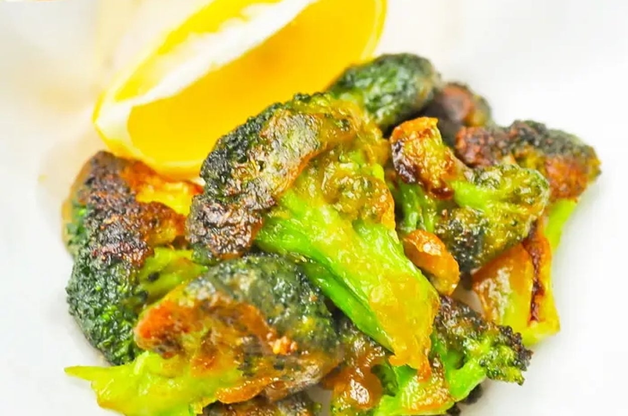 ブロッコリーのローストがクッキングシートにのせられ、レモンが添えられている。