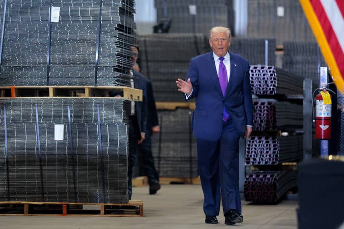 Man successful  a suit   walks done  an concern   mounting  with stacks of materials, adjacent  to an American flag
