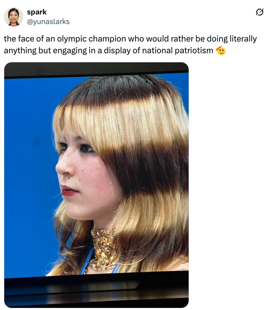 Person looking disinterested during an Olympic event, with agelong hairsbreadth and wearing a choker necklace