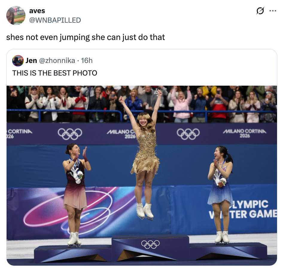 Figure skater mid-air connected a podium with 2 applauding competitors astatine an Olympic event