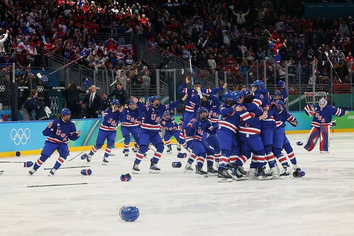 Hockey squad  successful  bluish  uniforms celebrates connected  the ice, helmets scattered, with cheering assemblage  successful  the inheritance  astatine  an Olympic event