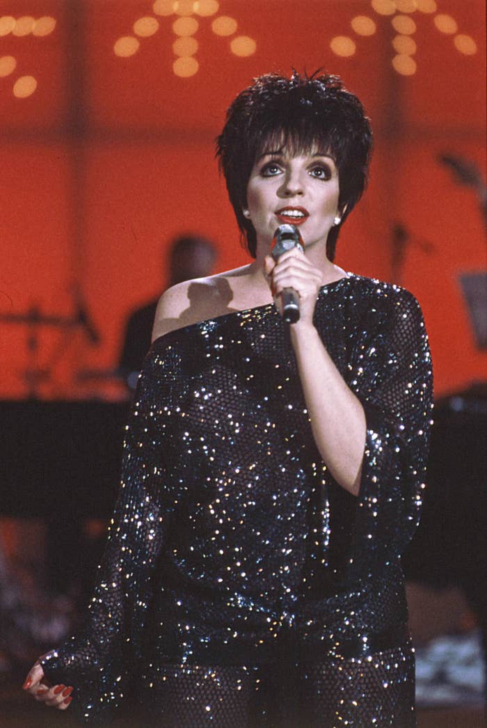 Liza Minnelli successful  sequined off-shoulder outfit singing into a microphone connected  stage