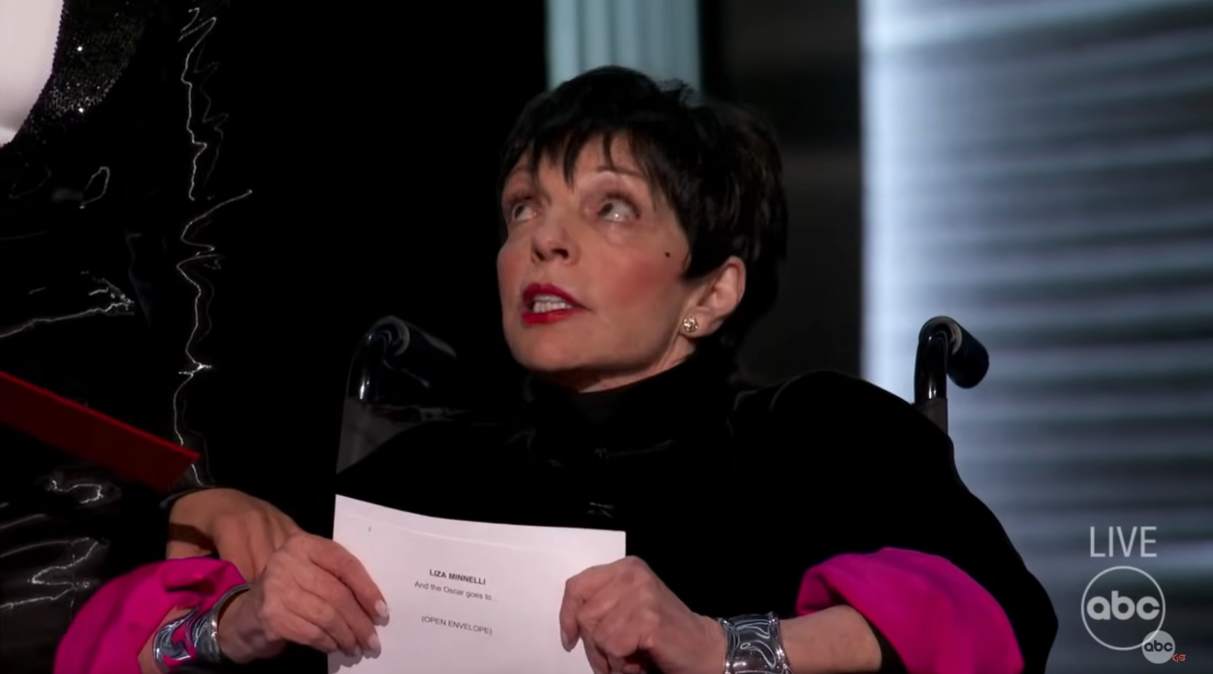 Liza Minnelli successful  a wheelchair holding an Academy Awards envelope connected  stage, wearing ceremonial  attire