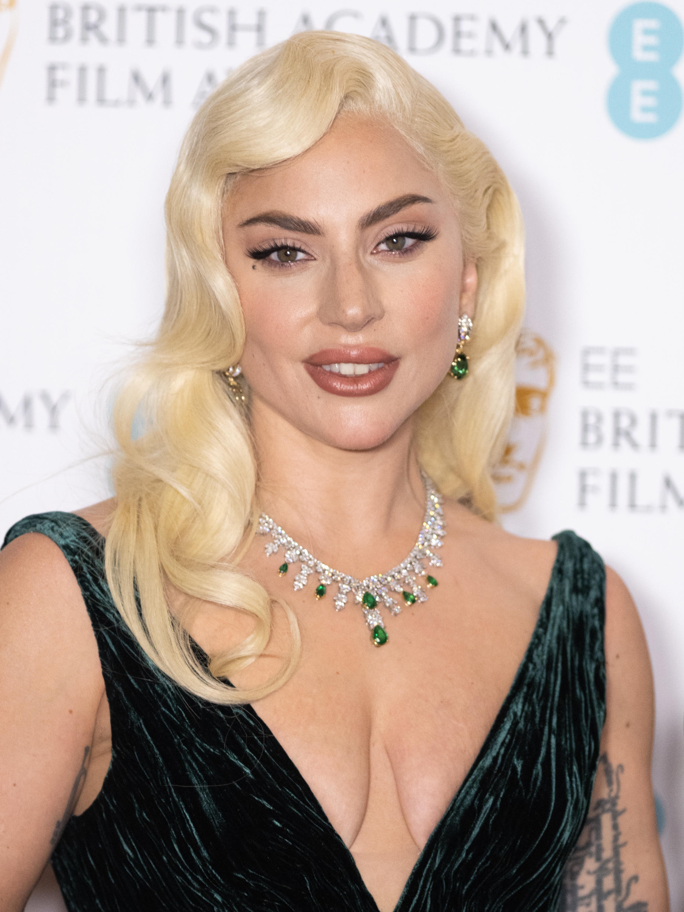 Lady Gaga with curled hairsbreadth  successful  an elegant velvet gown, featuring a heavy  neckline, poses astatine  a movie  awards event