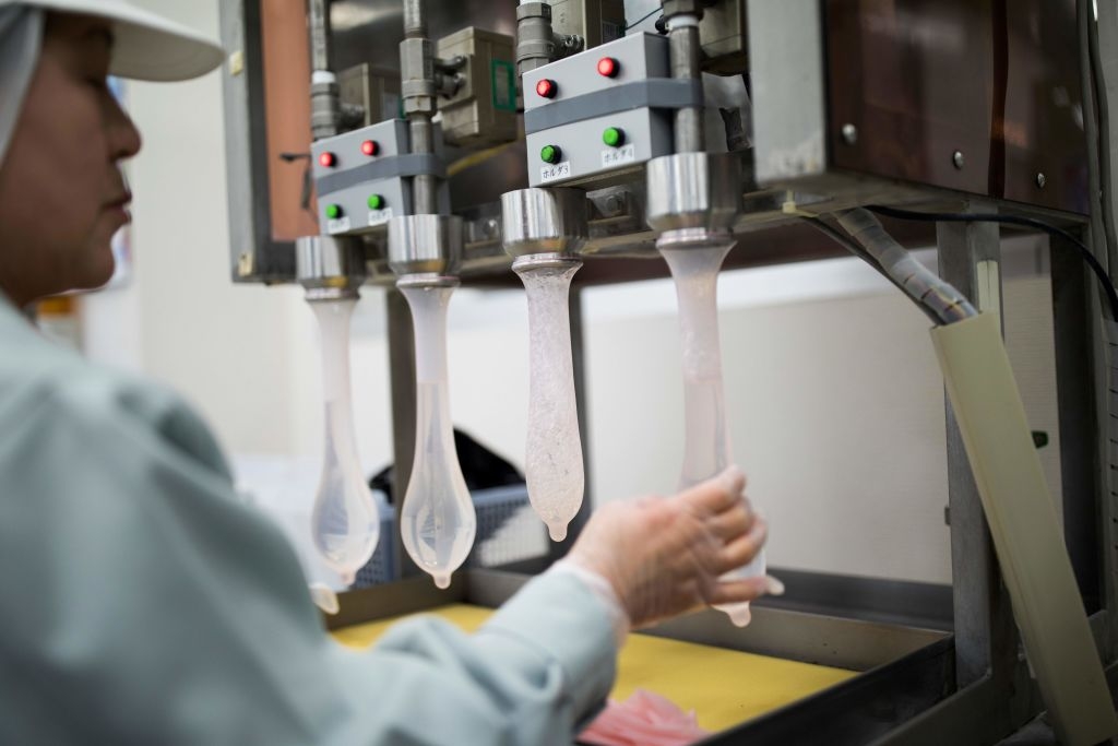 Arbeider som driver en matforedlingsmaskin på en fabrikk, og overvåker innholdet som fylles i hylser