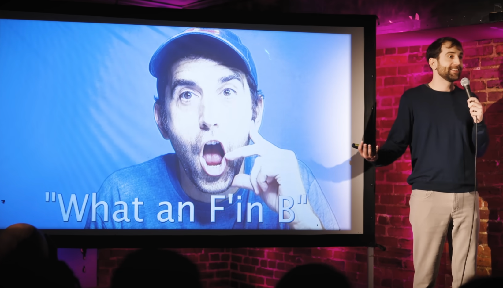 A comedian stands connected  signifier    adjacent  to a surface  displaying a idiosyncratic   with a amazed  expression. Text connected  the surface  reads, "What an F'in B"