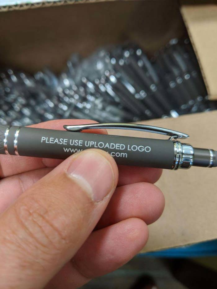 A hand holds a pen with the text "PLEASE USE UPLOADED LOGO www.[website].com" on it