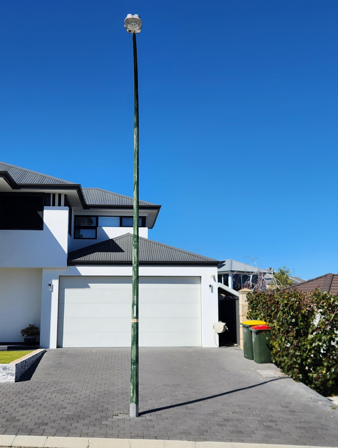 Streetlight pole positioned in the middle of a driveway leading to a garage