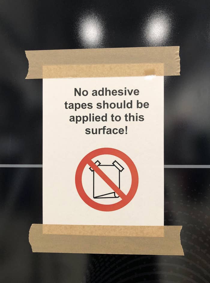 Sign prohibiting adhesive tape on surface, with red circle and slash over tape roll illustration