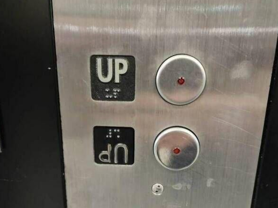 Elevator panel with two buttons labeled "UP" and another "UP" that's upside-down instead of a "Down" button