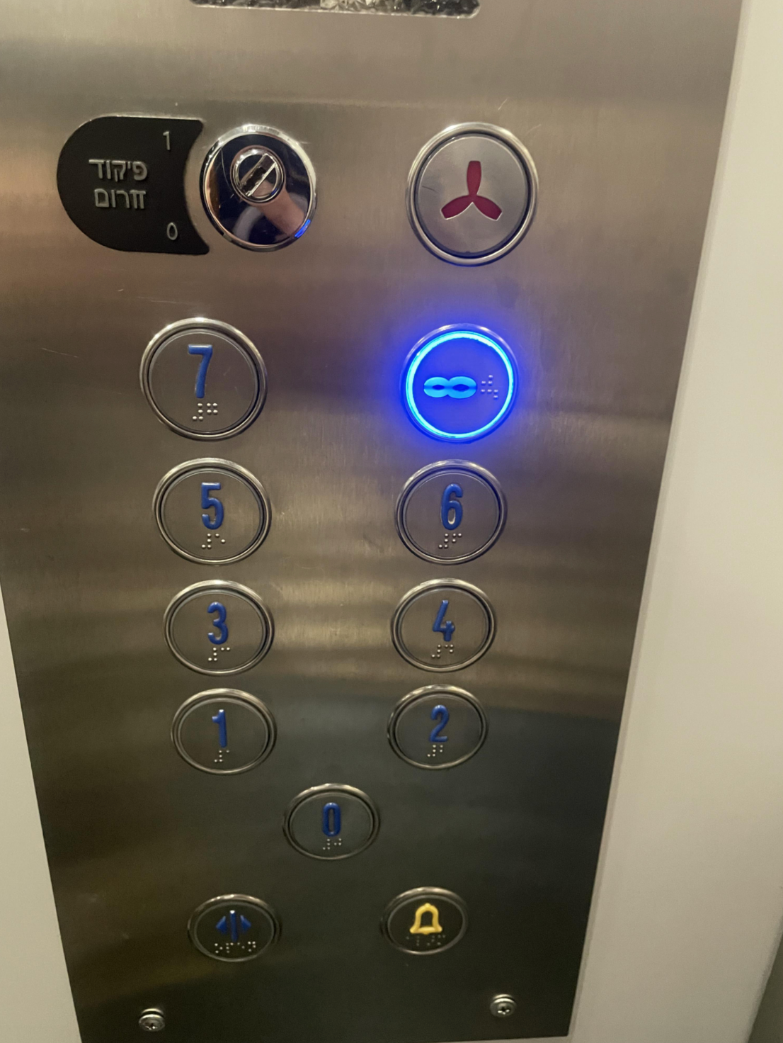 Elevator control panel with buttons for floors 0-7 and the button for floor 8 is sideways looking like  an infinity symbol