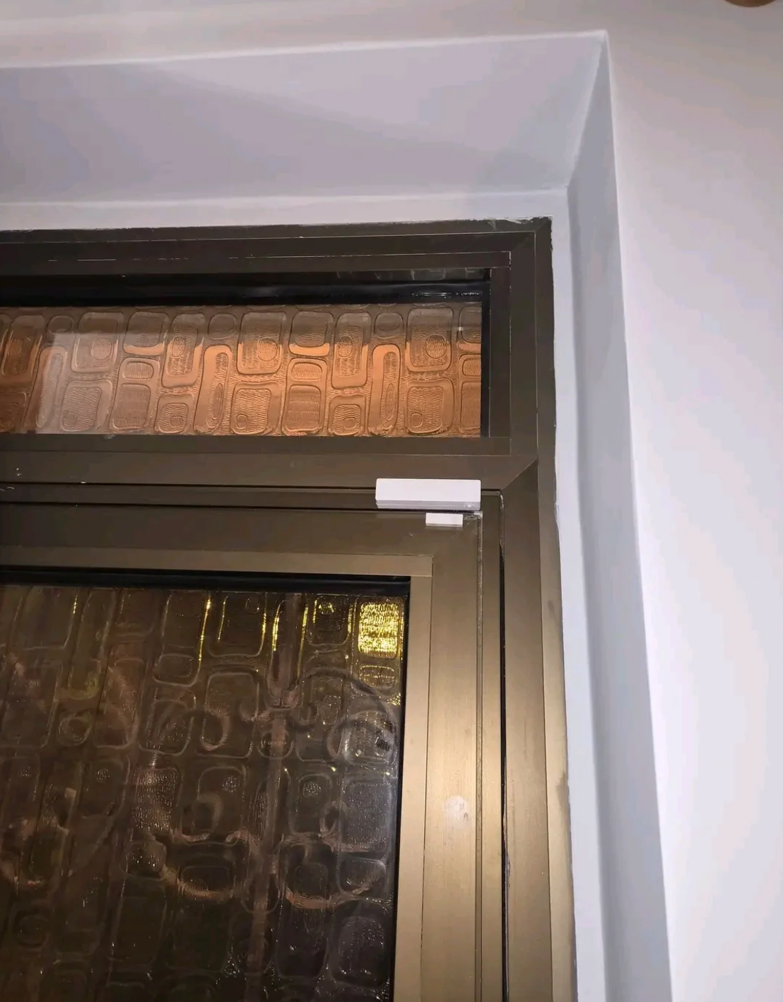 A window with frosted glass and a sliding lock mechanism, set within a white wall