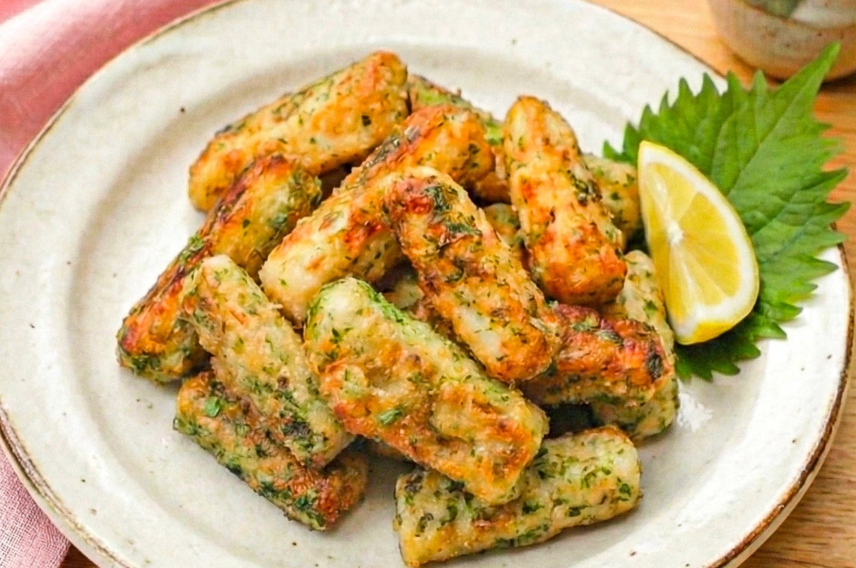 お皿に盛られた揚げ出し豆腐の天ぷらがあり、レモンとシソの葉が添えられています。食欲をそそる盛り付けです。