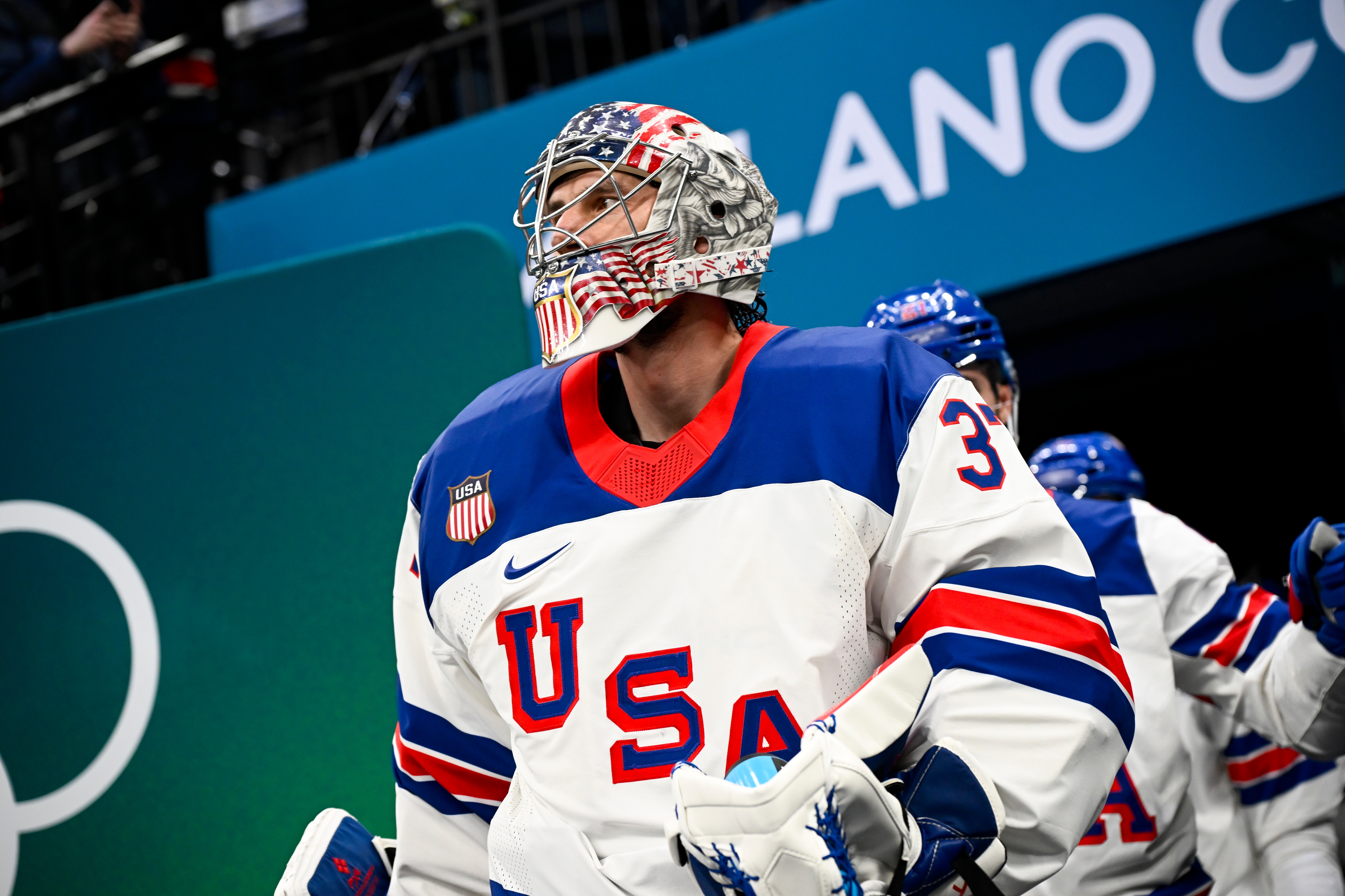 Hockey goalie successful USA uniform, helmet with emblem design, looks upward, lasting connected an crystal rink earlier a game